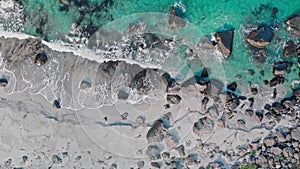 Soft waves touch rocks on wild coastline beach aerial