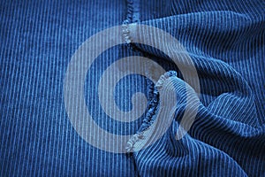 Soft wavy folds on the corduroy. Durable ribbed fabric. Close-up. Detail. Blue fabric backdrop with copy space