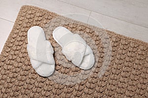 Soft white slippers on carpet in room. Space for text