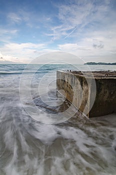 Soft white wave hitting concrete structure on the beach