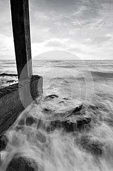 Soft white wave hitting concrete structure on the beach