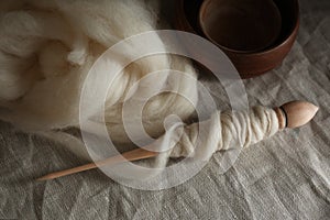 Soft white wool and spindle on table, above view