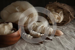 Soft white wool and spindles on table, closeup