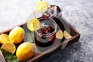 Softdrink with ice cubes, lemon and straw in glass.