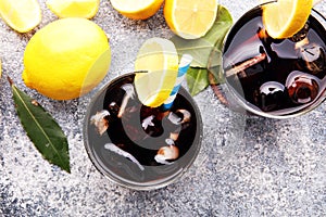 Softdrink with ice cubes, lemon and straw in glass.