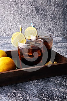 Softdrink with ice cubes, lemon and straw in glass.