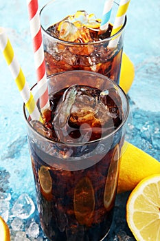 Softdrink with ice cubes, lemon and straw in glass.