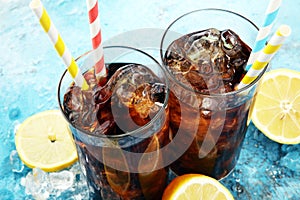 Softdrink with ice cubes, lemon and straw in glass.