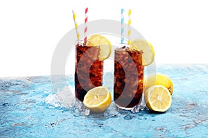 Softdrink with ice cubes, lemon and straw in glass.