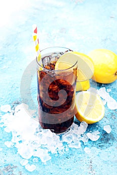Softdrink with ice cubes, lemon and straw in glass.