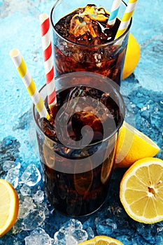 Softdrink with ice cubes, lemon and straw in glass.