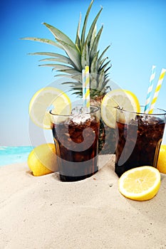 Softdrink with ice cubes, lemon and straw in glass.