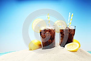 Softdrink with ice cubes, lemon and straw in glass.