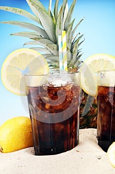 Softdrink with ice cubes, lemon and straw in glass.