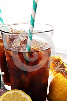 Softdrink with ice cubes, lemon and straw in glass