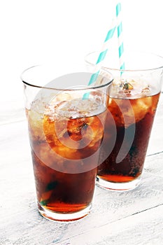 Softdrink with ice cubes, lemon and straw in glass