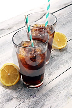 Softdrink with ice cubes, lemon and straw in glass