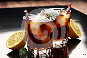 Softdrink with ice cubes, lemon and straw in glass