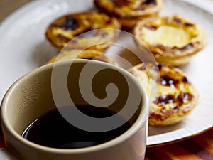 Softfocus custard tarts and black coffee cup