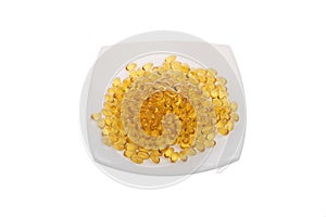 Softgels of Omega-3 on a white plate. Vitamins fish oil on a white background. Yellow capsules with medicine. Meal