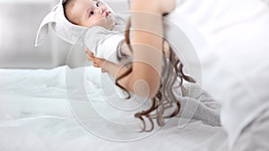 Softness mother hand taking little cute baby waking up on bed enjoying morning at white interior