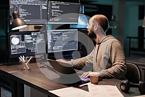 Software developer coding database on multiple monitors