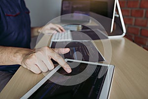 Software developer is pointing to the paper working and analyzing together the code written into the program on the computer