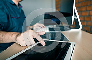 Software developer is pointing to the paper working and analyzing together the code written into the program on the computer