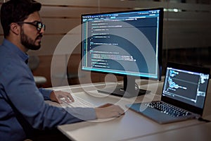 Software developer programmer working late on computer in dark office.
