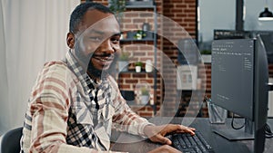 Software developer typing programming code on computer keyboard turning head and smiling