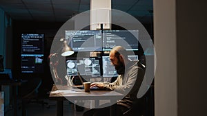 Software developer typing source code on laptop and multiple monitors