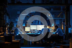 Software developers coding on computers in dark office at night