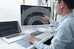 Software development concept, Male programmer checking data codes on document and computer screen