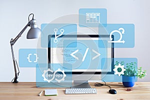 Software development workplace in bright office with wooden table, programming coding code on desktop computer screen, IT