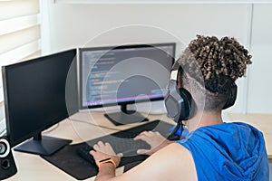 Software engineer sitting at desk and typing on computer keyboard while creating code while working at home