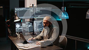 Software engineer typing source code on multiple monitors
