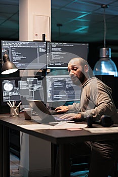 Software engineer writing code on multiple screens