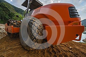 Soil compactor with vibratory padfoot drum. Heavy duty machinery working on highway construction site. Vehicle for soil