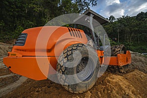 Soil compactor with vibratory padfoot drum. Heavy duty machinery working on highway construction site. Vehicle for soil