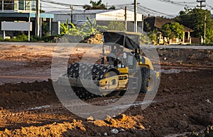 Soil compactor with vibratory padfoot drum. Heavy duty machinery working on highway construction site. Vehicle for soil