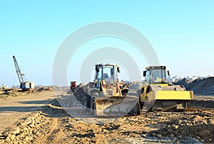 Soil Compactor and  wheel loader at construction site. Vibration single-cylinder road roller leveling the ground for the construct