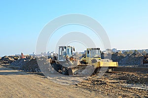 Soil Compactor and  wheel loader at construction site. Vibration single-cylinder road roller leveling the ground for the construct