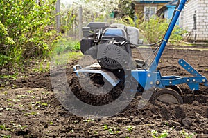 Soil cultivation. Moto cultivator loosens the ground for planting. The farmer plows the field. Agriculture