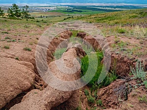 Soil erosion, deep ravine in the distance. Scenic view to colorful unusual relief. Picturesque gorge in highlands