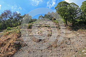 Soil erosion in the highlands. Landscape mountain with soil cracked. Rock outlier on background of mountains with forests, which a