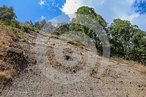 Soil erosion in the highlands. Landscape mountain with soil cracked. Rock outlier on background of mountains with forests, which a