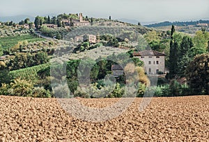 Soil for grapes of local farm in landscape of Tuscany with garden trees, mansions, green hills. Italian countryside