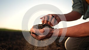 soil in the hands of the farmer. agriculture. close-up of a farmers hands holding black soil in sun their hands, fertile
