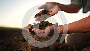 soil in the hands of the farmer. agriculture. close-up of a farmers hands holding black soil in their hands, sun fertile