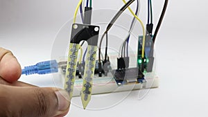 Soil moisture sensor or soil humidity meter connected with jumper wires and OLED display board on a breadboard circuit for an